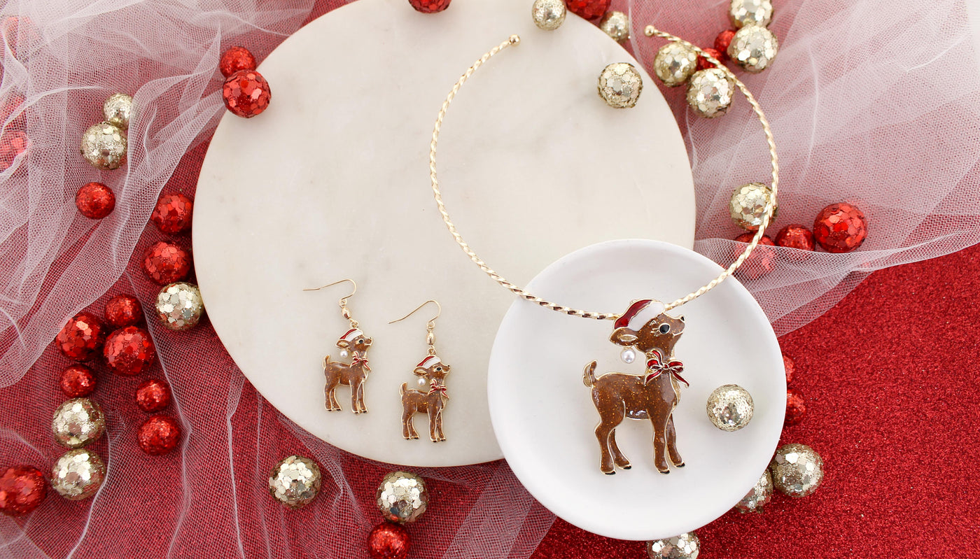 Reindeer-themed earrings on a white dish with red and gold decorative elements.
