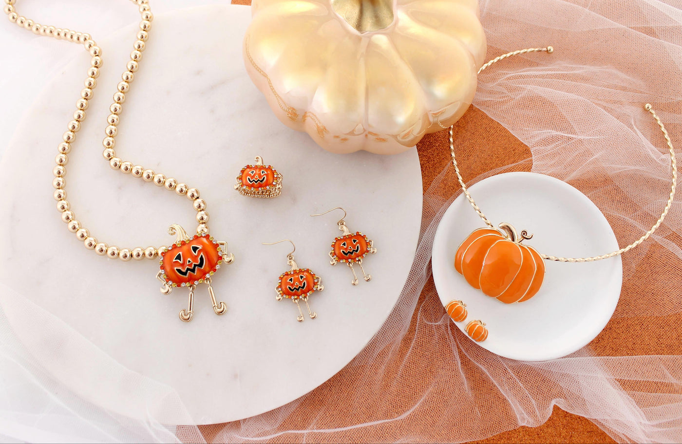 Halloween-themed jewelry set with pumpkin design on a white and orange fabric background